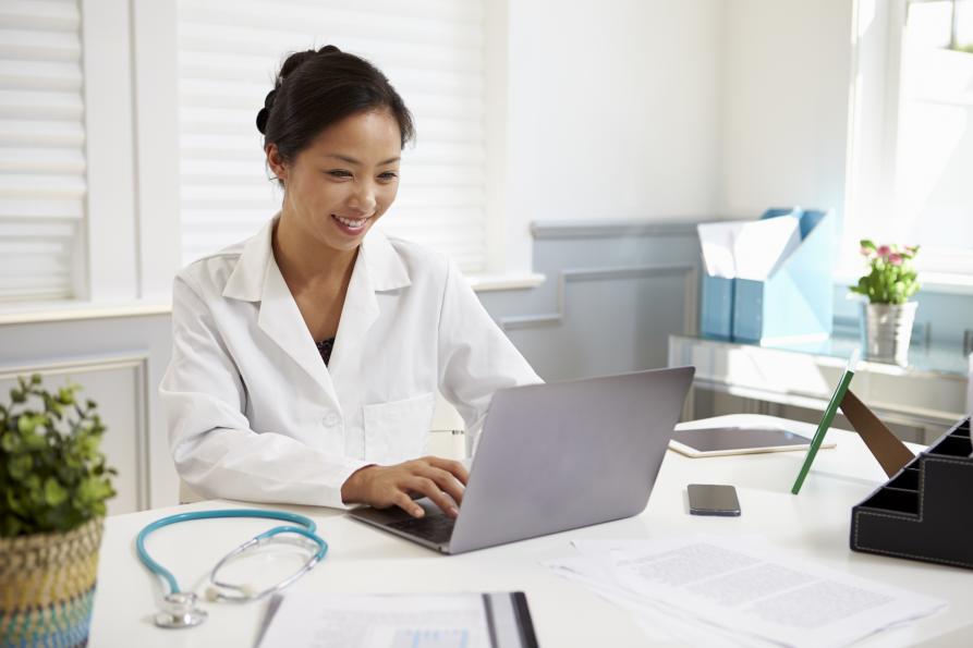Doctor seated at desk before laptop